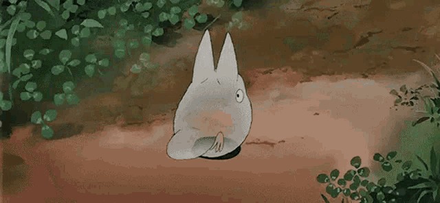 a totoro from the movie my neighbor totoro is sitting on the ground in the dirt .