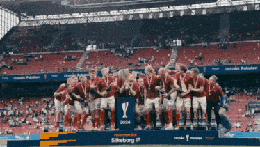 a group of soccer players celebrate with a trophy that says silkeborg if 2024