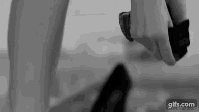 a black and white photo of a woman taking off her shoes .