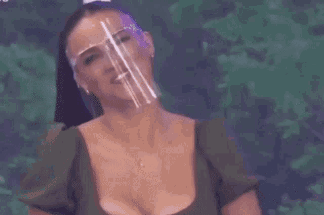 a woman wearing a face shield and glasses is smiling on a television show .