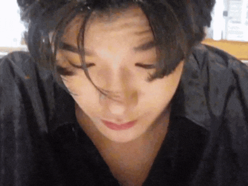 a close up of a person 's face with their eyes closed and their hair blowing in the wind .