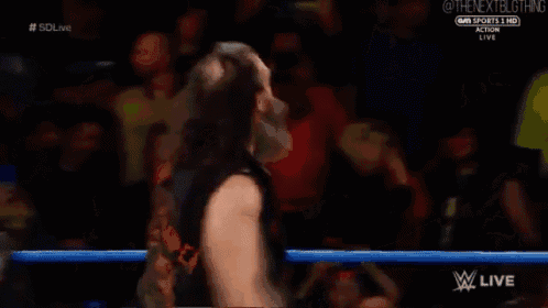a man with a beard is standing in a wrestling ring with his arms outstretched ..