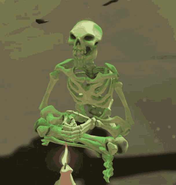 a green skeleton sits in a lotus position next to a candle