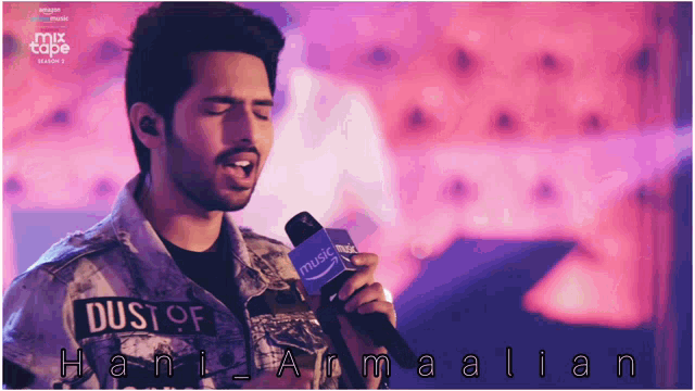 a man singing into a microphone with dust of hani armalian written on his jacket
