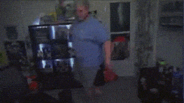 a man in a blue shirt is dancing in a room with posters on the wall