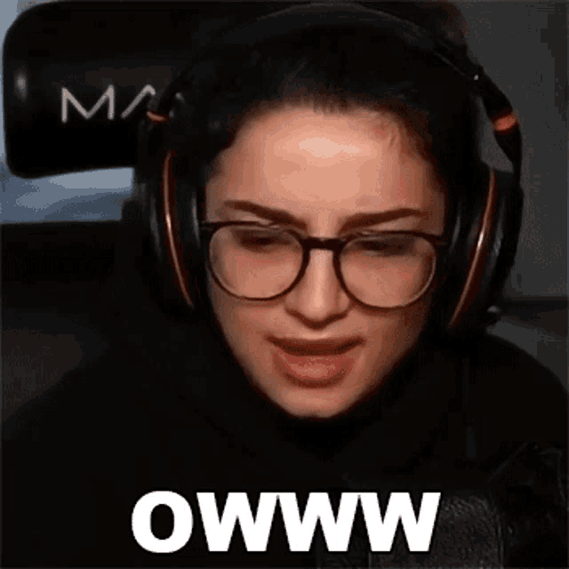 a woman wearing glasses and headphones is making a funny face with the words owww written on the bottom .