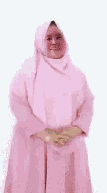 a woman wearing a pink hijab and a pink sweater is dancing .