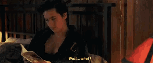 a young man is laying on a bed with a magazine in his hand and says `` wait ... what ? ''