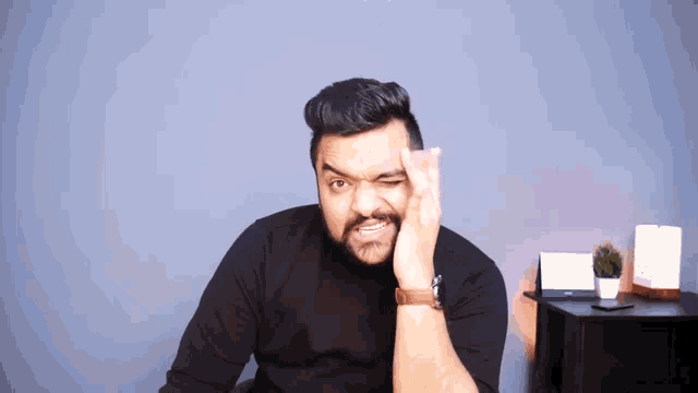 a man with a beard is making a funny face with his hand to his forehead