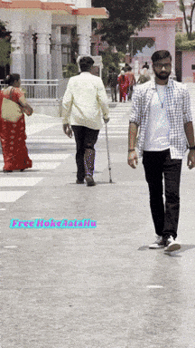 a man with a cane walks down a street with a woman in a red dress behind him