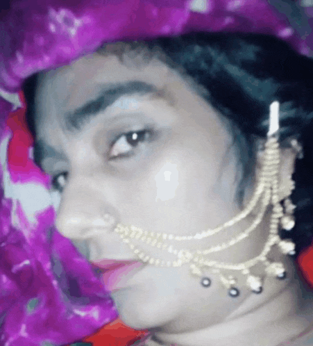 a woman wearing a nose ring and a necklace looks at the camera .