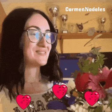 a woman wearing glasses is smiling in front of a shelf with trophies and the name carmennadales on it
