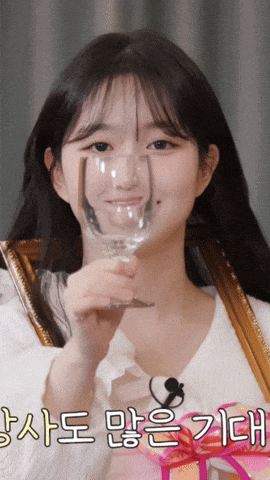 a woman is holding a wine glass in front of her face with korean writing on the bottom