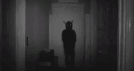 a shadow of a devil with horns is standing in a hallway .