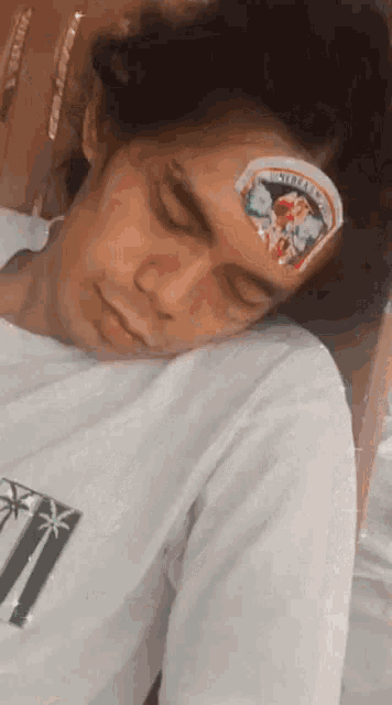 a man with a sticker on his forehead sleeping