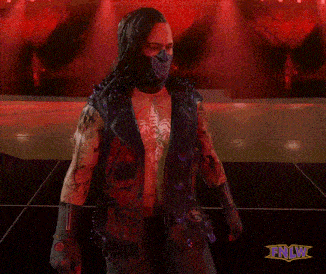 a man wearing a mask and a vest with spikes is standing in front of a sign that says tnlw