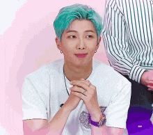 a man with blue hair is wearing a white t-shirt and a purple watch .
