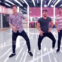 three men are dancing in a room with a pink wall