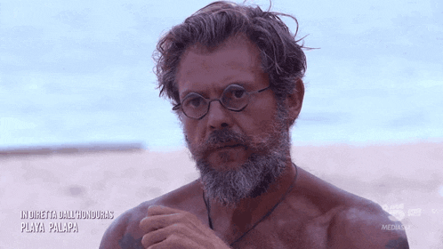 a man with glasses and a beard is on a beach