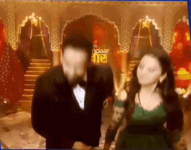 a man and woman are dancing in front of a sign that says ndaar
