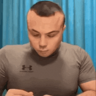 a man wearing a gray under armour shirt is sitting at a table .