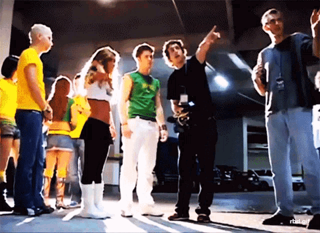 a group of people are standing in a room and one of them has a green shirt on