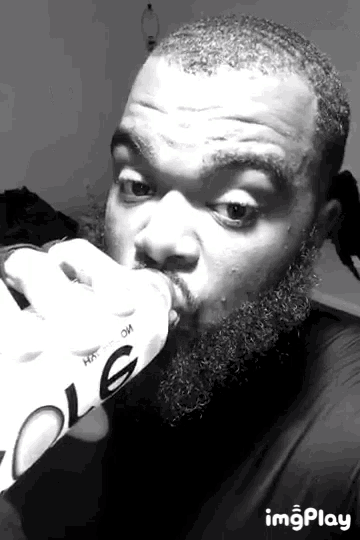 a black and white photo of a man drinking from a bottle that says cola