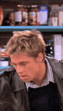 a man in a leather jacket stands in front of a shelf full of food items