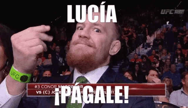 a man in a suit and tie is making a funny face in front of a crowd and a sign that says lucia pagale