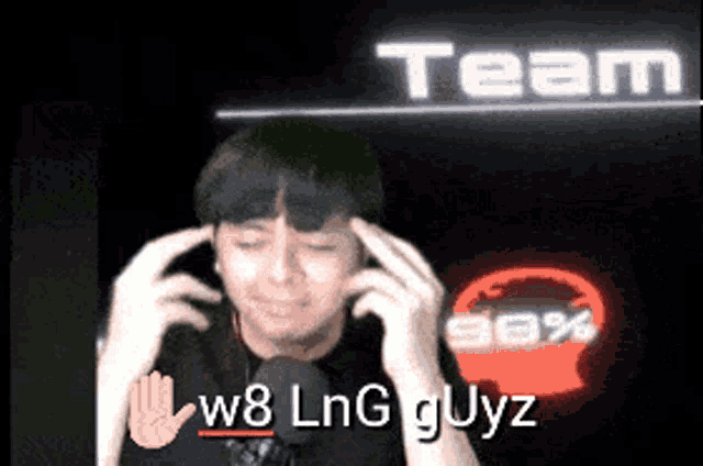 a man holds his hands to his head in front of a sign that says team w8 lng guyz