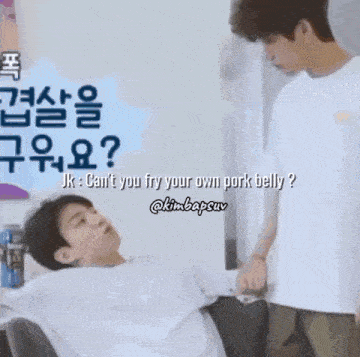 two men are standing next to each other and one of them is laying down .