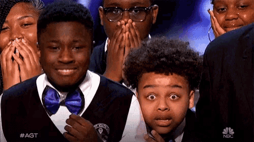 a group of young boys are covering their mouths with their hands while watching a show called agt on nbc
