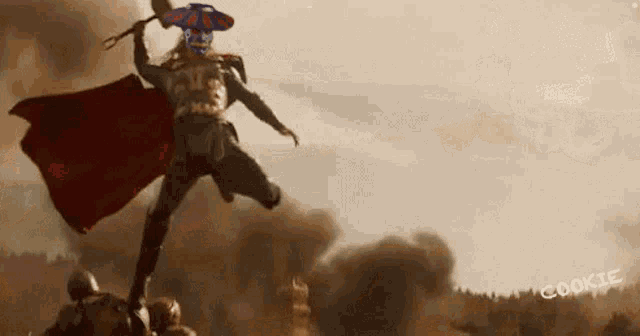 a man with a red cape is holding a hammer in his hand while standing on a hill .