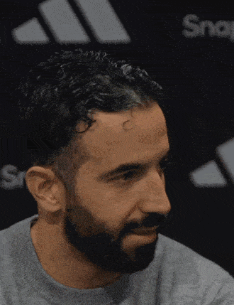 a man with a beard wearing a grey shirt with the word sport on it