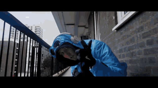 a man wearing a blue jacket and headphones is standing on a balcony