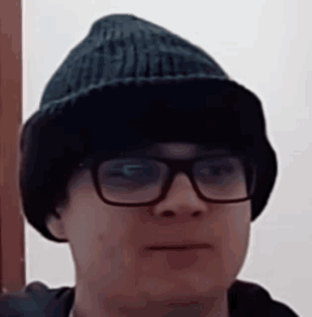 a man wearing a beanie and glasses looks at the camera .