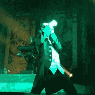 a man in a tuxedo is standing on a stage with a microphone in his hand