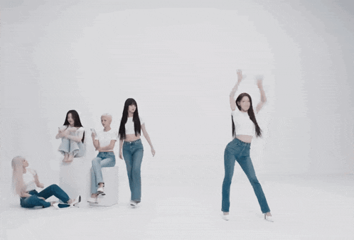 a group of women in white shirts and jeans are dancing in a white room