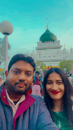 a man and a woman pose for a picture in front of a temple
