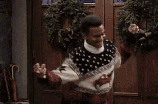 a man wearing a sweater with horses on it is dancing in front of a door .