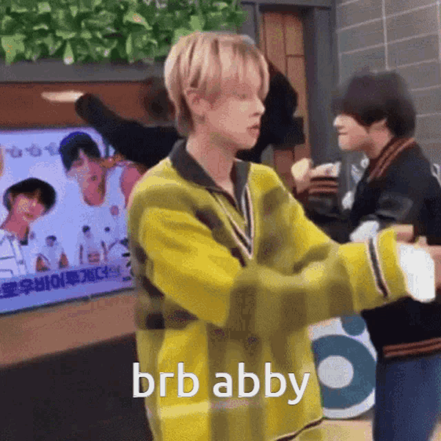 a man in a yellow sweater is hugging another man in front of a television screen .