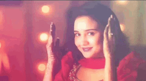 a woman with henna on her hands is smiling and waving .