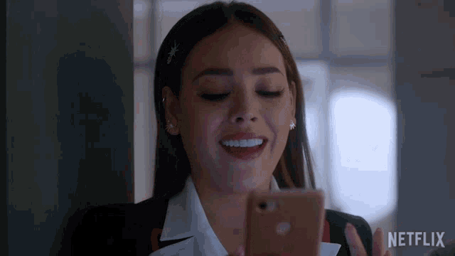 a woman is smiling while holding a cell phone with netflix written on the bottom