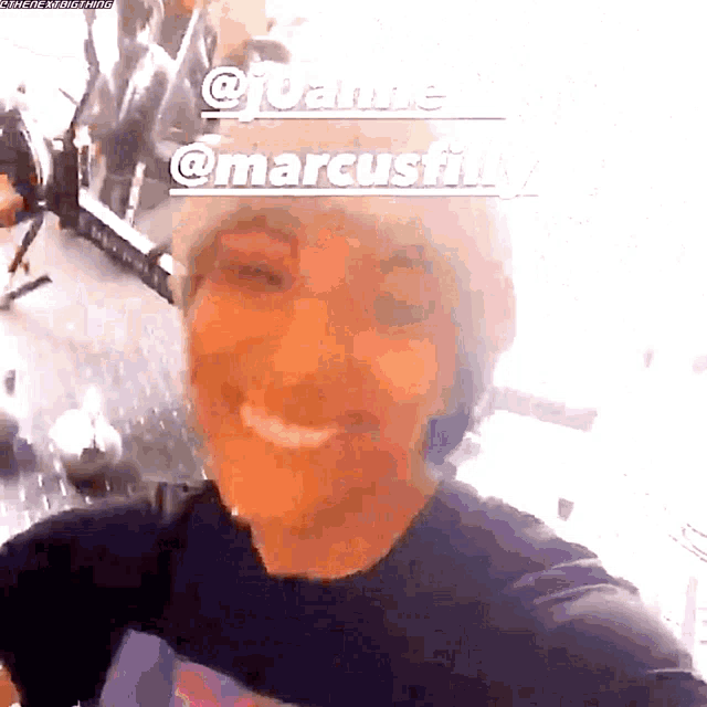 a woman is smiling in front of a sign that says marcusfly