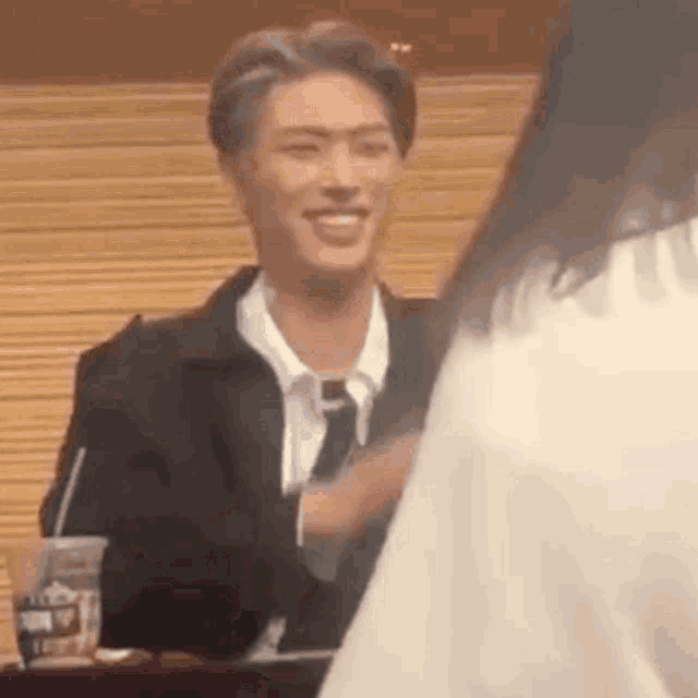 a man in a suit and tie is smiling while talking to a woman in a white shirt .