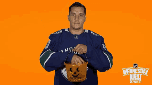 a man in a vancouver jersey holds a pumpkin bucket