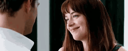 a man and a woman are looking at each other . the woman is smiling and the man is looking at her .