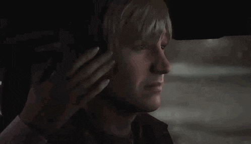 a man with blonde hair is sitting in the back seat of a car .