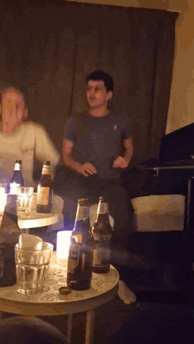 a man sits on a couch with a bottle of corona beer on a table