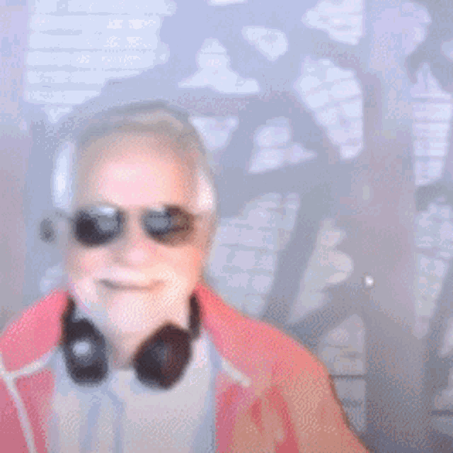 a man wearing headphones and sunglasses is pointing at the camera